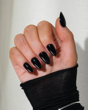 Black Press-on Nails on a hand white a black long sleeved jumper